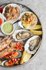 Metal tray with open oysters, raw mussels and caviar. Seafood assortment. On a stone background. Free space for text