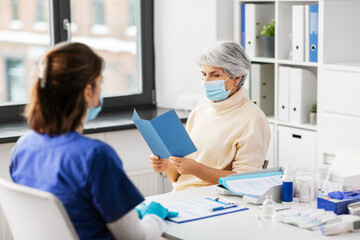 medicine, health and vaccination concept - doctor or nurse and senior woman reading medical brochure at hospital
