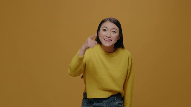 Furious adult arguing in front of camera, raising finger in frustration, standing over yellow background. Irritated woman having argument and aggressive reaction, showing indignation.