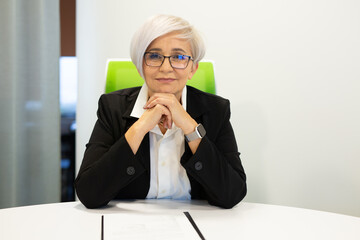adult stylish woman aged in glasses at the table with documents 