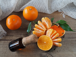 Tangerine slices, leaves, peel, tincture, oil juice in a bottle on a wooden table, top view, flat layout. Citrus reticulata healthy fruits with vitamin C