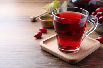 Glass cup of fresh dogwood tea and berries on wooden table. Space for text