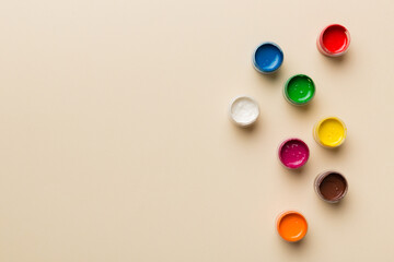 jars with gouache of different colors on Colored background. hobby painting. Top view with empty space. workplace for creativity. home teaching concept drawing