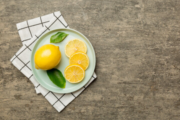 Fresh cutted lemon and whole lemons over round plate on colored background. Food and drink ingredients preparing. healthy eating theme top view vith copy space