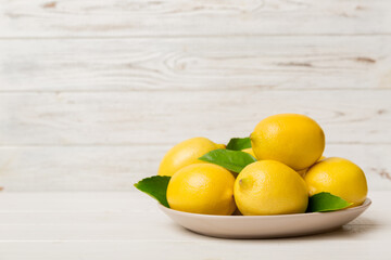 Fresh cutted lemon and whole lemons over round plate on colored background. Food and drink ingredients preparing. healthy eating theme top view vith copy space