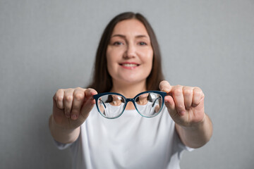 close-up of glasses with magnifying lenses on blurred young woman background.