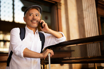 Happy senior man waiting a train. Man talking to the phone while waiting a train. Man preparing for...