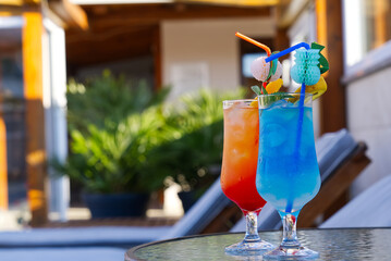 Blue Lagoon Beach Cocktail and Sex on the beach Cocktail in front of a blue swimming pool. summer cocktail with copy space