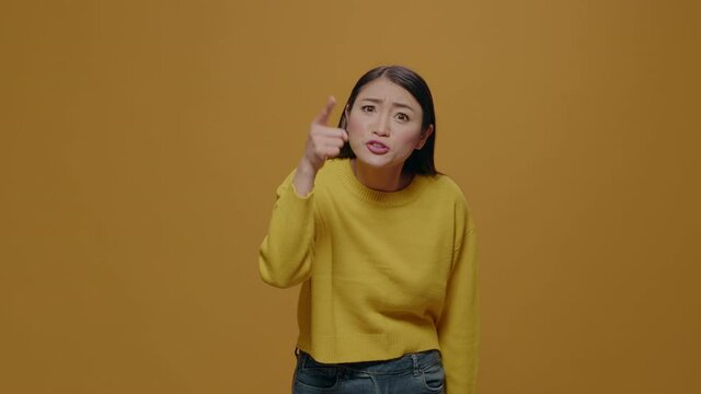 Angry woman showing index finger at camera and having argument, feeling furious and insulted in studio. Offended person arguing and having negative reaction, annoyed facial expression.