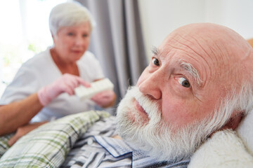 Kranker Senior im Bett im Pflegeheim und Altenpflegerin