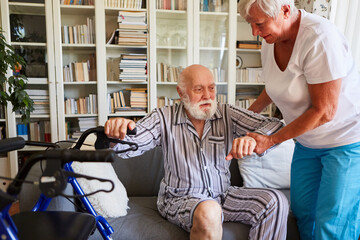 Altenpflegerin hilft Senior beim Aufstehen von Sofa zu Hause