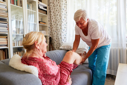 Physiotherapeutin behandelt das Knie einer Seniorin