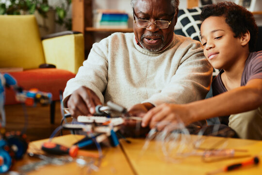A grandad and grandson making a robot together at home. Education in robotics and electronics.