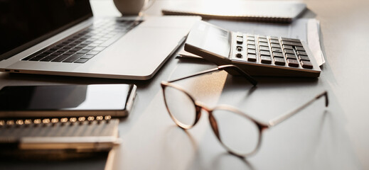 Accountant workplace, calculator, laptop computer and glasses at office desk panoramic banner, finance, business and accounting concept