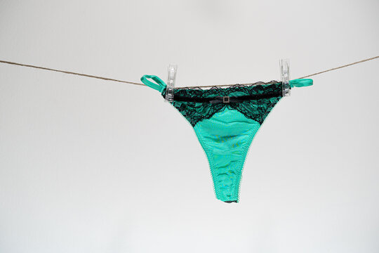 Green women's thong panties on a clothesline fastened with white pegs.