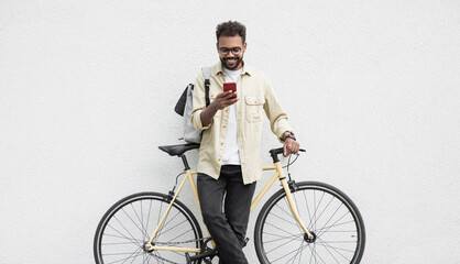 Young handsome man with bicycle over white wall background in a city, cheerful student men with...