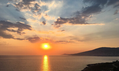 Bright beautiful colorful sunset with clouds on the sea with rocks