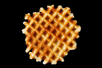 One Belgian waffle on a black background. View from above. Close-up.