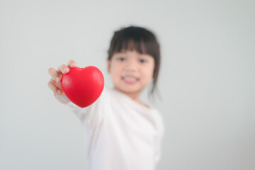 The little girl in a white shirt holding a red heart on a white background. Greeting cards for valentine's day, mother's day, father's day.