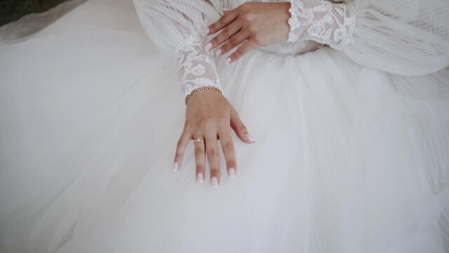 The bride in a wedding dress sits and slowly touches her hands
