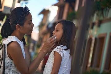 Asian mother wiping clean the face of her cute young daughter 