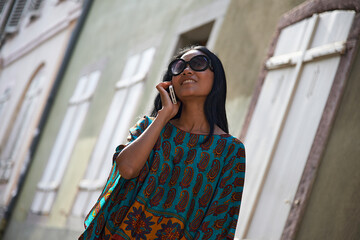 Asian woman talking on her mobile phone in summer sunshine