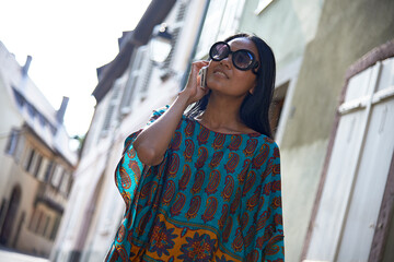 Asian woman talking on her mobile phone in summer sunshine