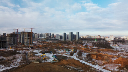 Construction site. Construction of modern high-rise buildings. Work construction cranes. Snow covered earth. Aerial photography.