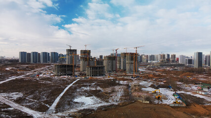 Construction site. Construction of modern high-rise buildings. Work construction cranes. Snow covered earth. Aerial photography.