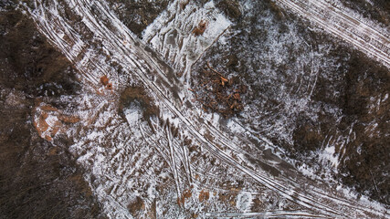 Construction site in a city vacant lot. Traces of heavy construction equipment are visible on the ground. Snow covered earth. Aerial photography.