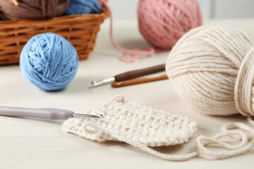 Fototapeta na wymiar Knitting, crochet hook and clews on white wooden table