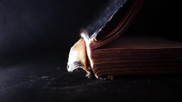 Closing pages of an old worn book on dark smoke background