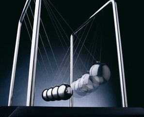 Newtonpendel mit 5 silbernen Kugeln vor dunklem Hintergrund