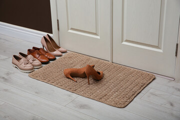 Stylish shoes and door mat in hall