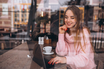 Woman in cafe drinking coffee and talking on the phone
