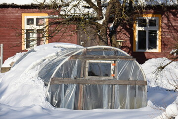 Winter greenhouse near farm house on snow - 480927200