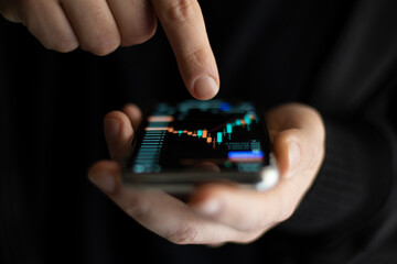 Businessman working with smartphone, thinking and analyzing graph stock market trading with stock chart data planning, financial and investment concept	