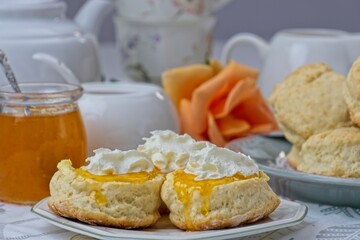 Close up of fresh scones topped apricot jam and whipped cream