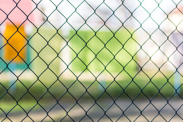 Fototapeta premium Blurred metal mesh on a blurred green background close-up