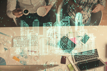 Double exposure of man and woman working together and the buildings hologram drawing. Computer background. Top View. Smart city concept.
