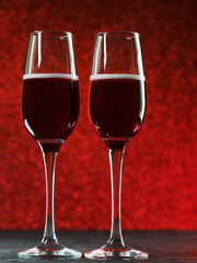two glasses of sparkling wine on a red block background