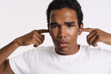 Young black man looking at camera while plugging his ears