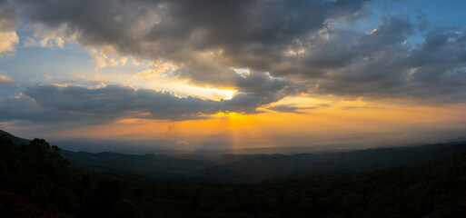 Panorama Dark cloud sunset over Dark mountain.Colorful sunrise with Clouds over hill.Sun hiding behind a cloud on the day sky.