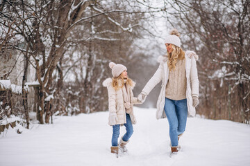Mother with daughter walking together in a winter park