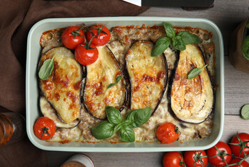 Delicious eggplant lasagna in baking dish on wooden table, flat lay