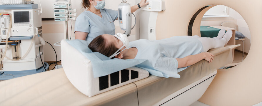 Doctor or nurse and patient with tomography CT or MRI Scan in hospital. Interior of radiography department. Technologically advanced equipment in white room. Magnetic resonance diagnostics machine