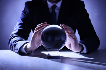 Businessman using crystal ball to predict future at table, closeup - obrazy, fototapety, plakaty