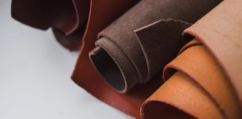 Deurstickers Rolls of genuine brown leather on a white background. Materials for leather goods. Manufacturing of leather goods. Banner © Anna