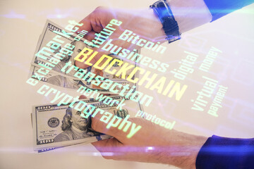 Multi exposure of blockchain theme drawing hologram and USA dollars bills and man hands. Business concept.
