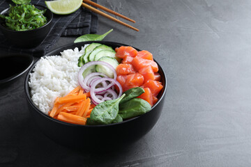 Delicious poke bowl with salmon and vegetables served on grey table. Space for text